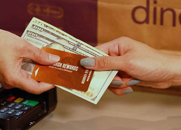Woman handing cash and Monarch Rewards card to cashier