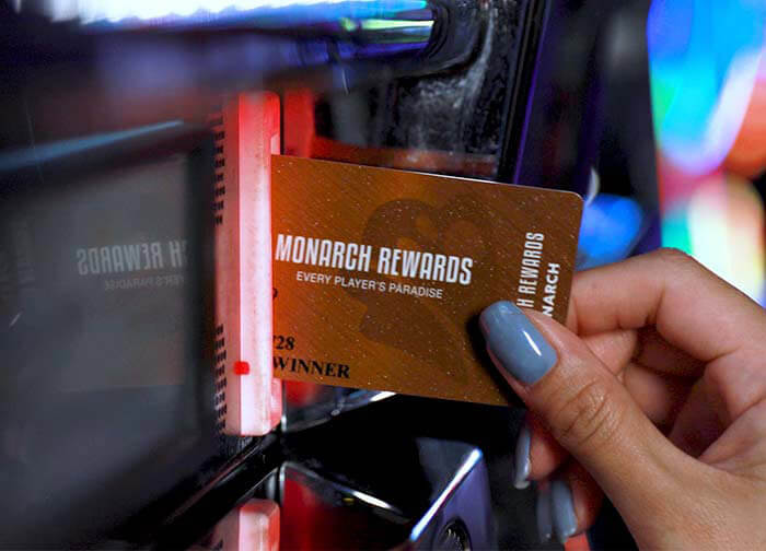 Woman inserting Monarch Rewards card into slot machine